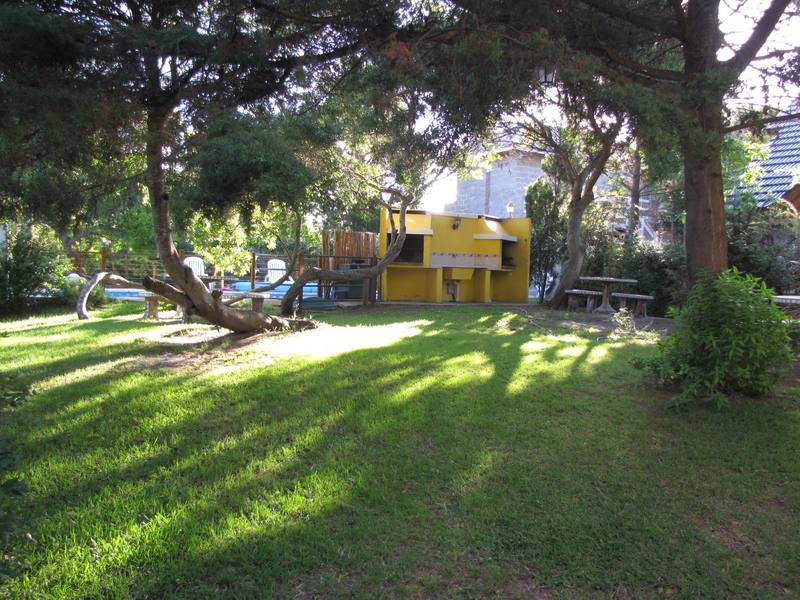 Parque privado con césped, árboles y juegos para chicos