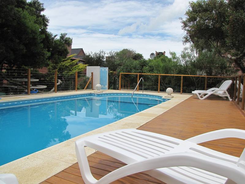 Piscina climatizada con deck de madera y reposeras
